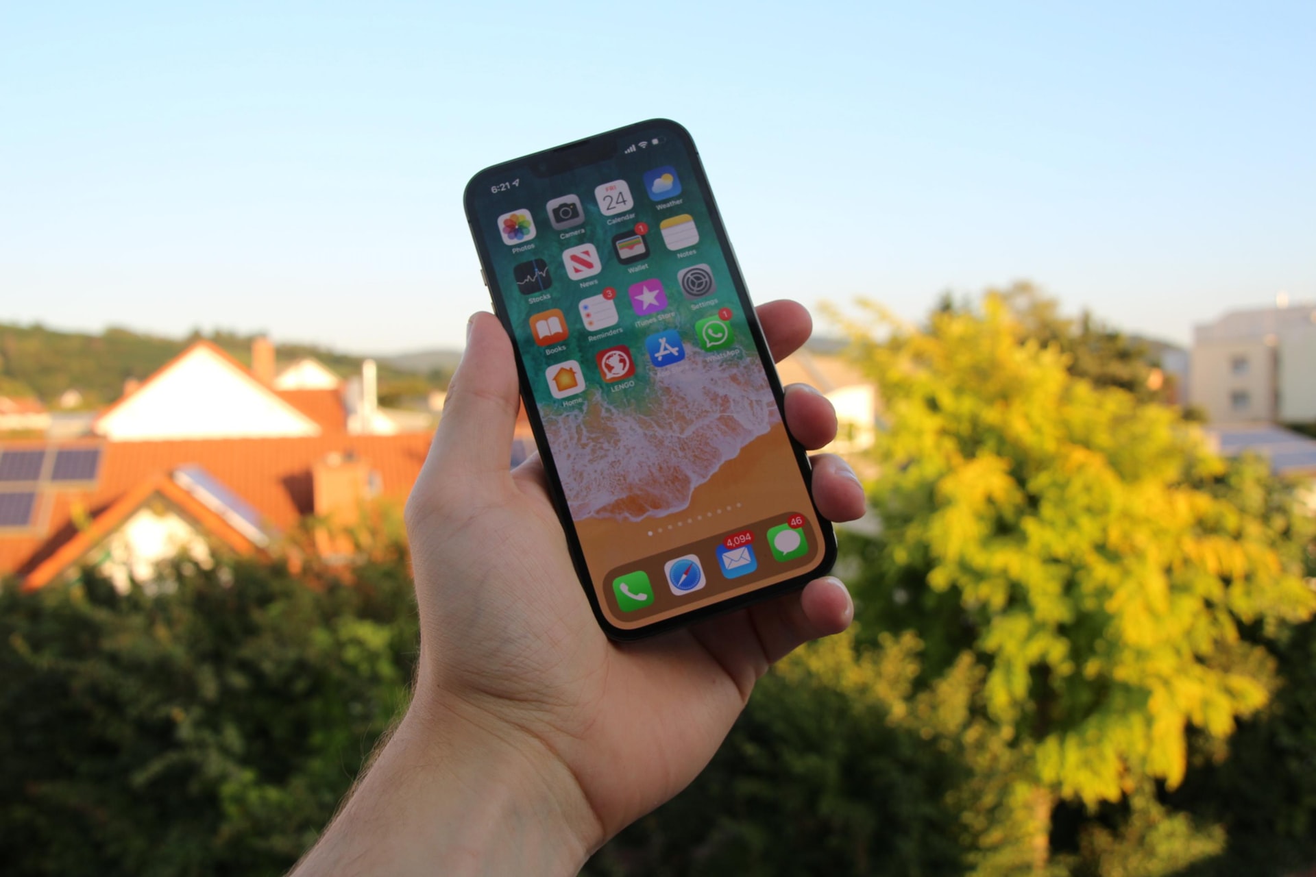 dłoń trzymająca odblokowany iPhone z listą aplikacji na pulpicie